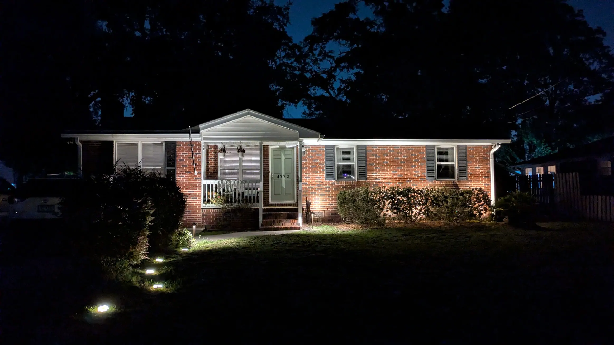 Charleston area home after landscape lighting with warm path lights and uplighting on trees and planting beds