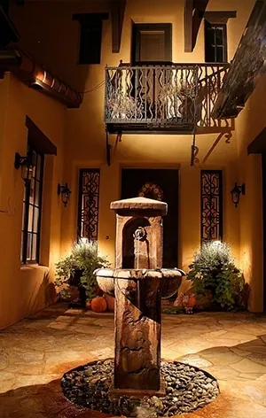 Architectural lighting on a covered outdoor living space with warm lights on columns and ceiling beams in Charleston SC