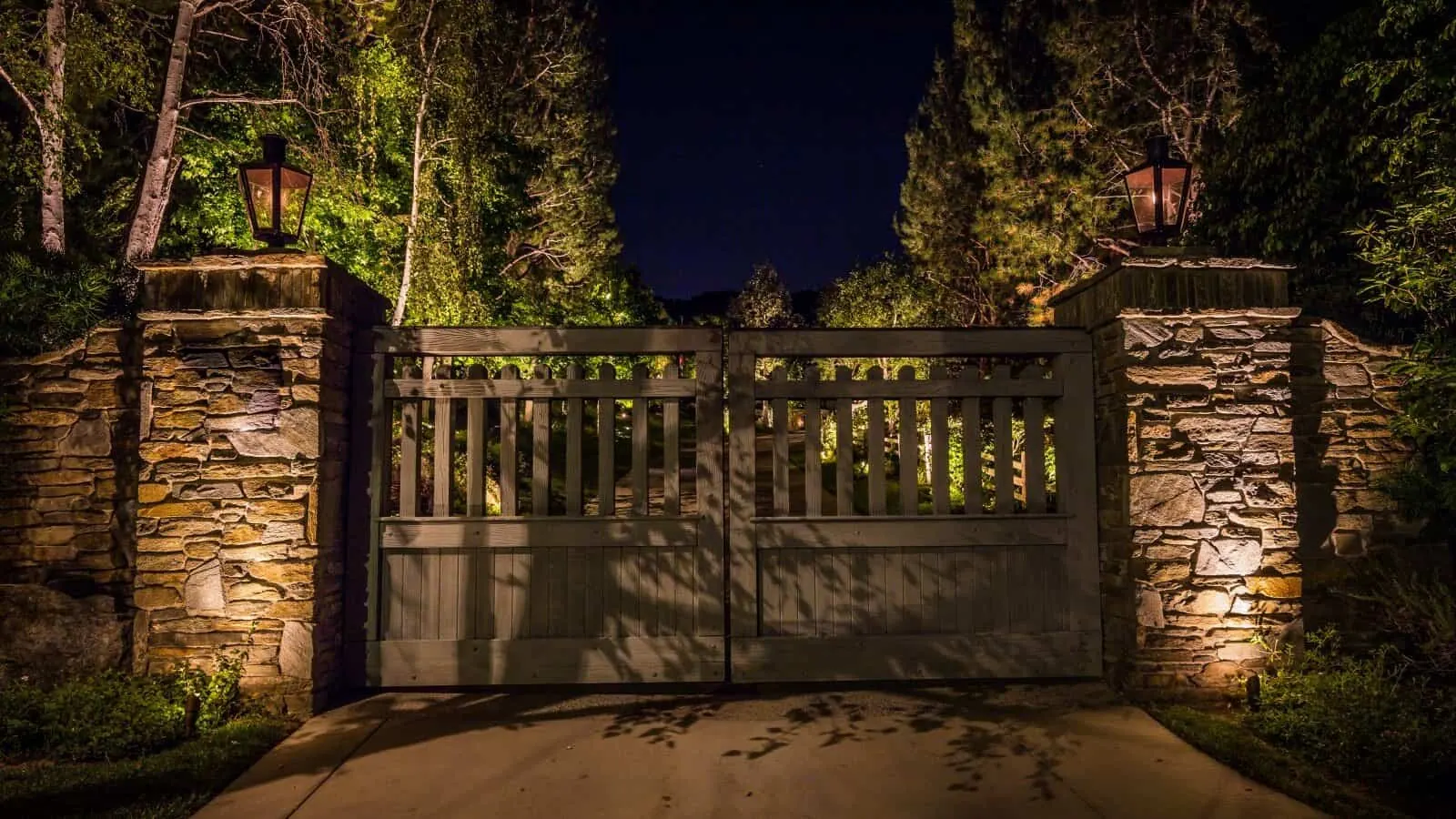 Stone entry gate and driveway illuminated with low voltage landscape lighting in Charleston SC